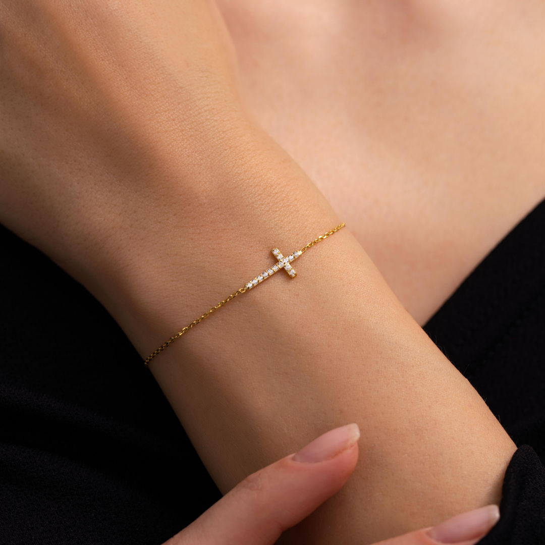 Gold-toned cross bracelet with stones worn on a wrist