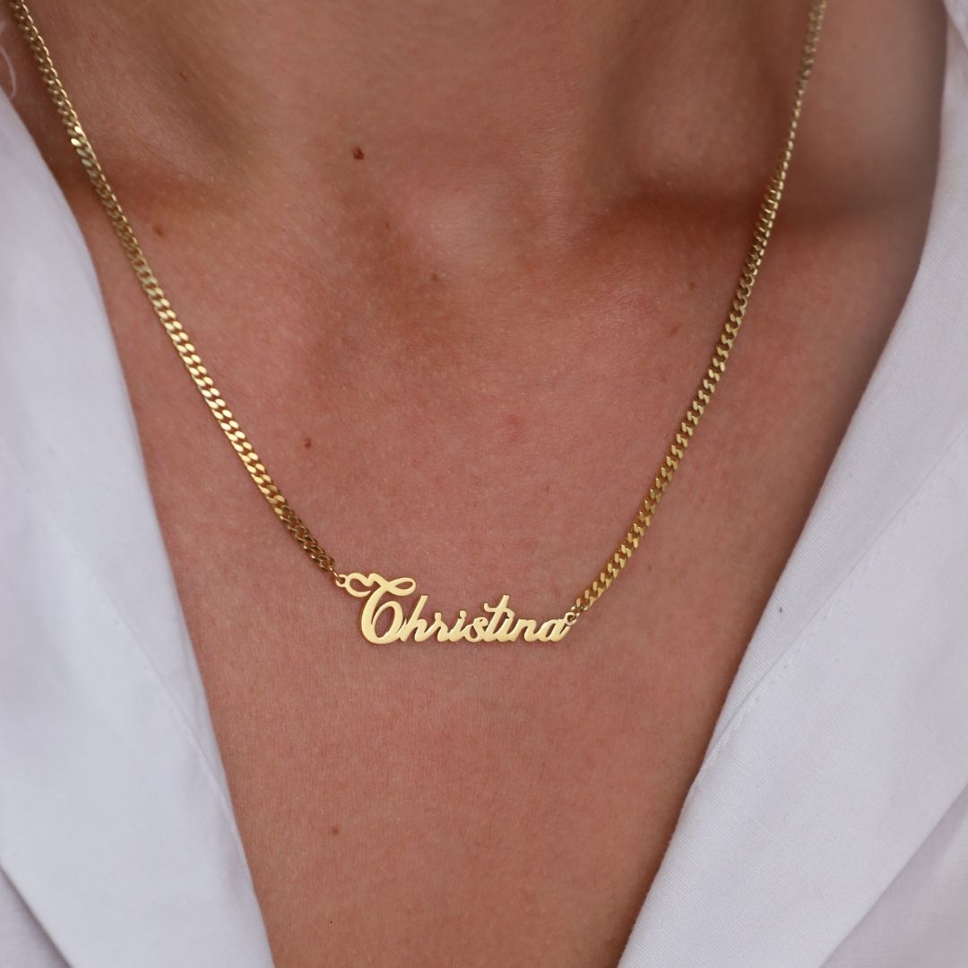 Gold-toned personalized Christina name necklace with a curb chain worn with a white shirt