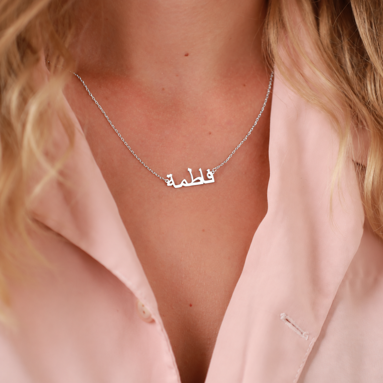 Personalized Arabic name necklace in sterling silver, worn with a pink shirt