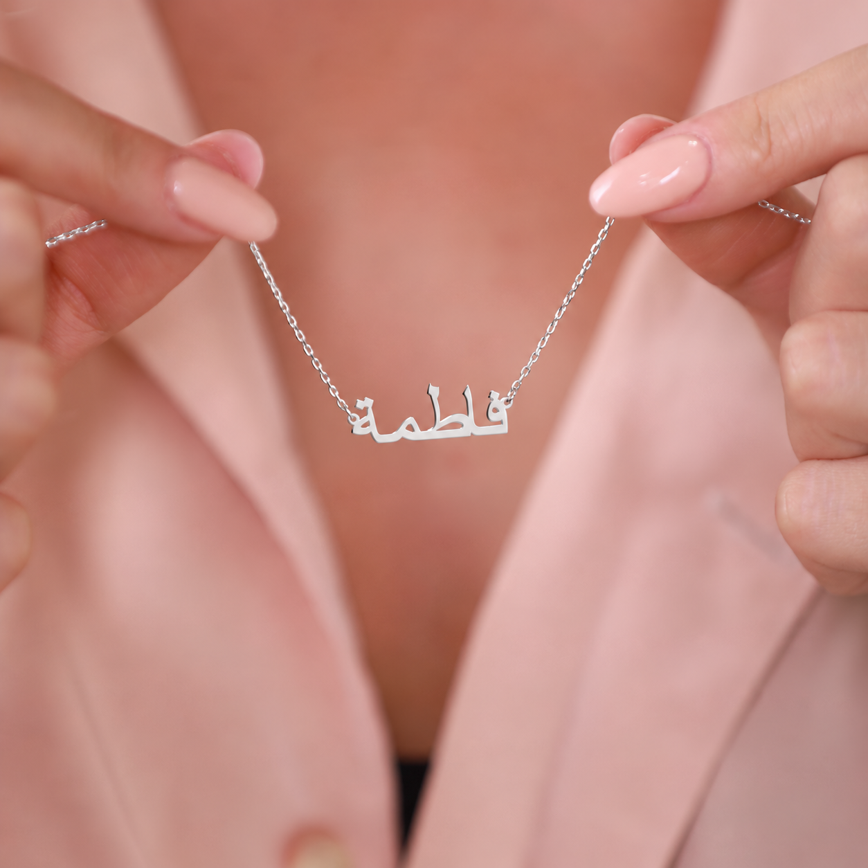 Personalized Arabic name necklace in solid white gold, held in both hands