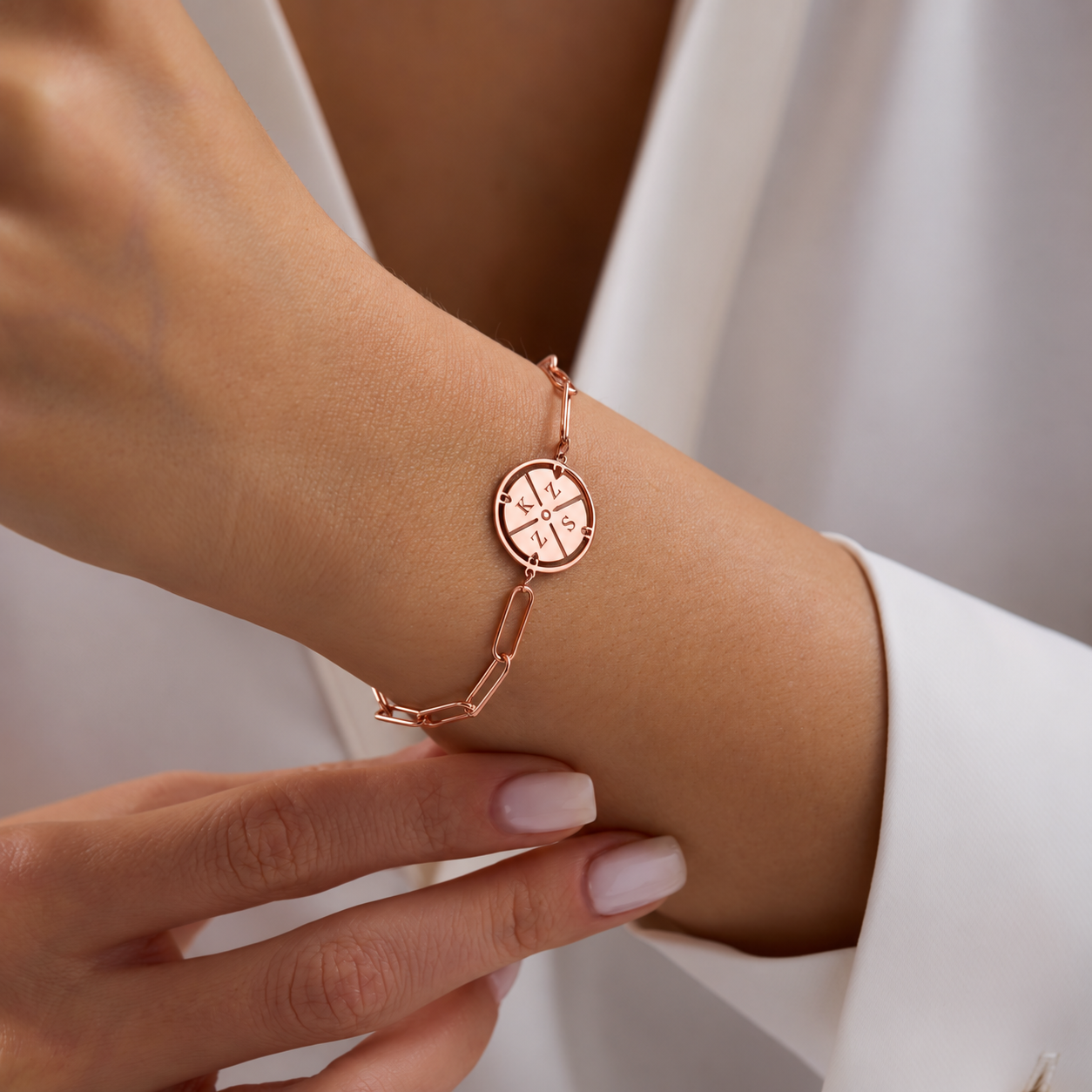 Custom engraved initial compass bracelet in 14K rose gold filled, with a paperclip chain worn on the wrist