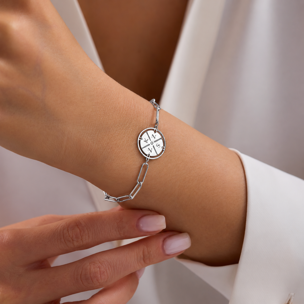 Custom engraved initial compass bracelet in sterling silver, with a paperclip chain worn on the wrist