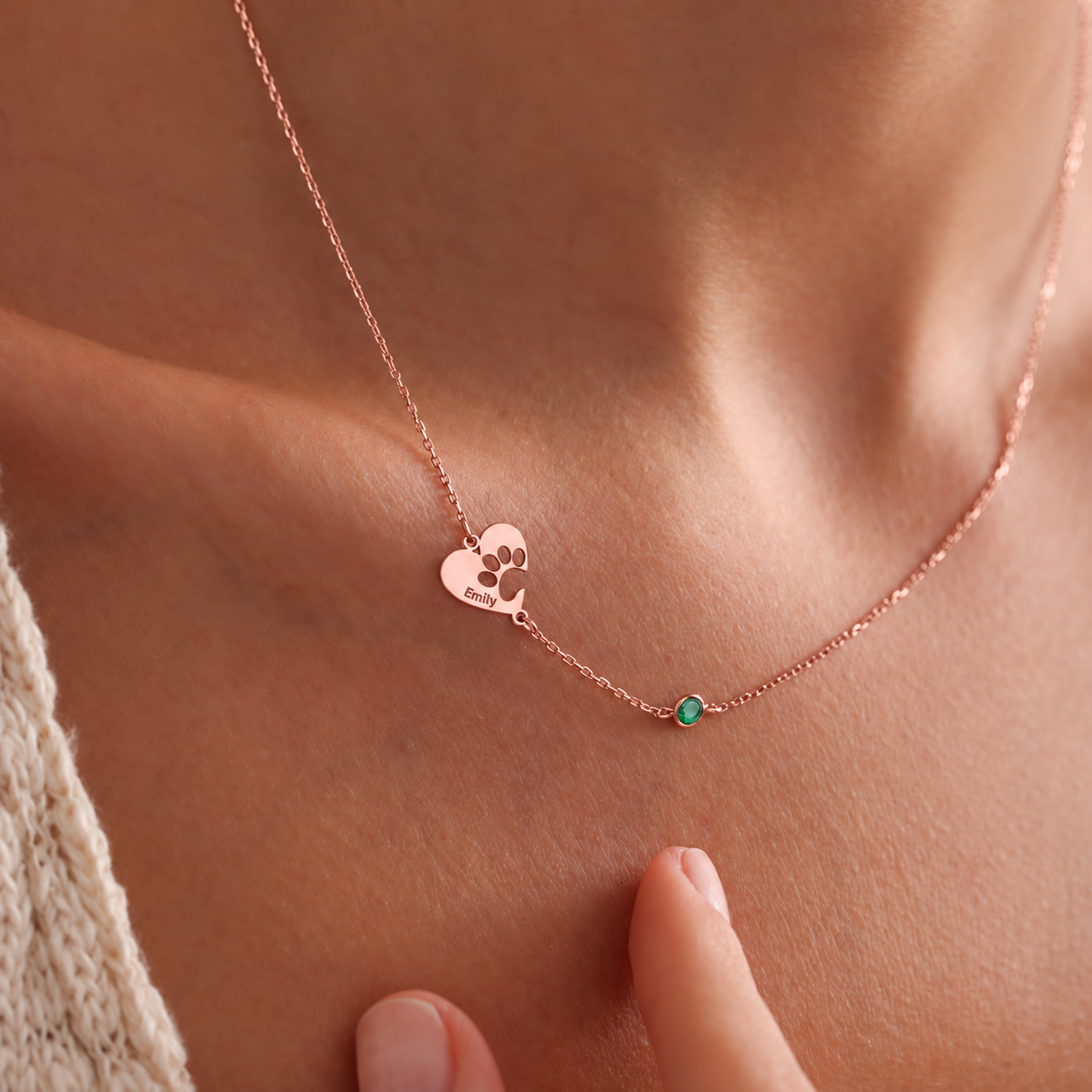 Custom engraved heart-shaped paw necklace in 14K rose gold filled with Emily engraving and a green birthstone, worn on the neck