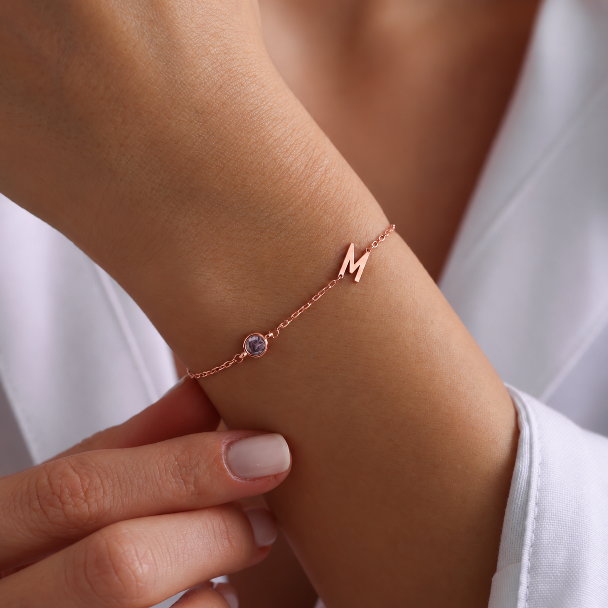 14K rose gold filled M initial birthstone bracelet with a round purple gemstone, worn on a wrist