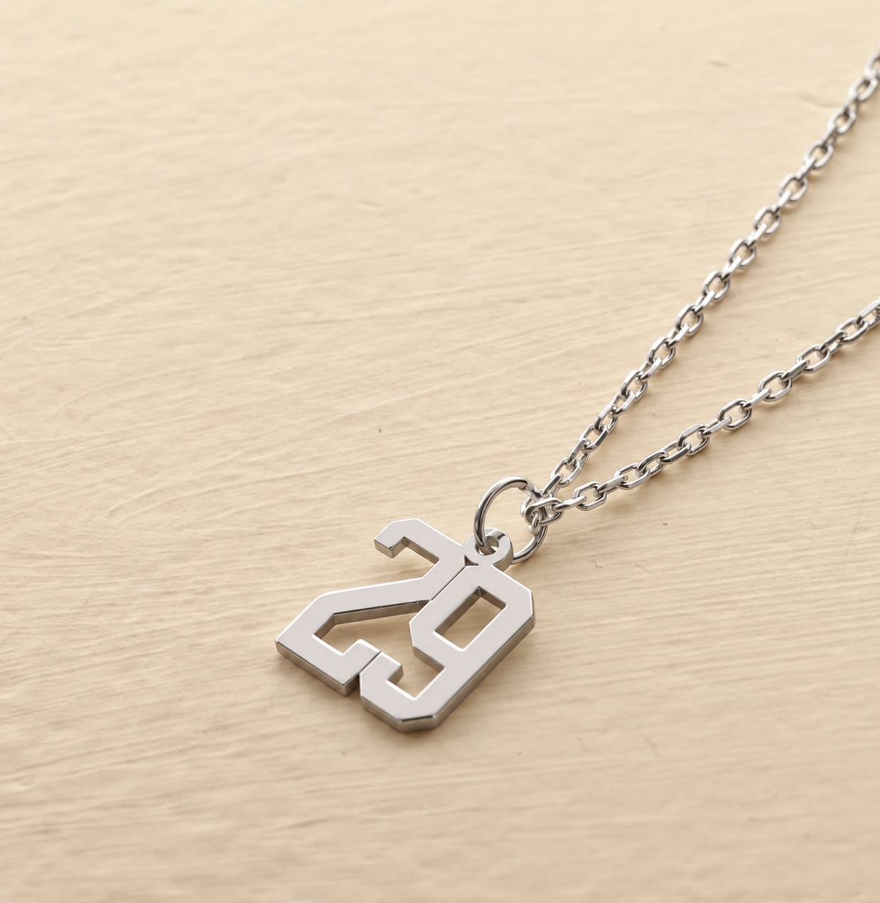 Custom number 29 necklace in 14K solid white gold on a light wooden background