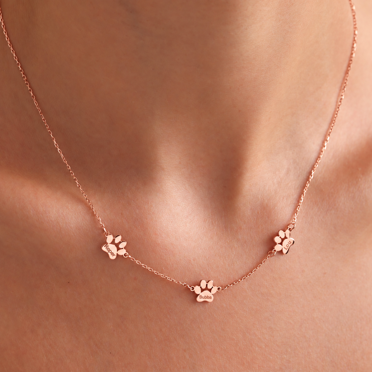 14K rose gold filled pet memorial necklace with three personalized paw charms, worn close-up