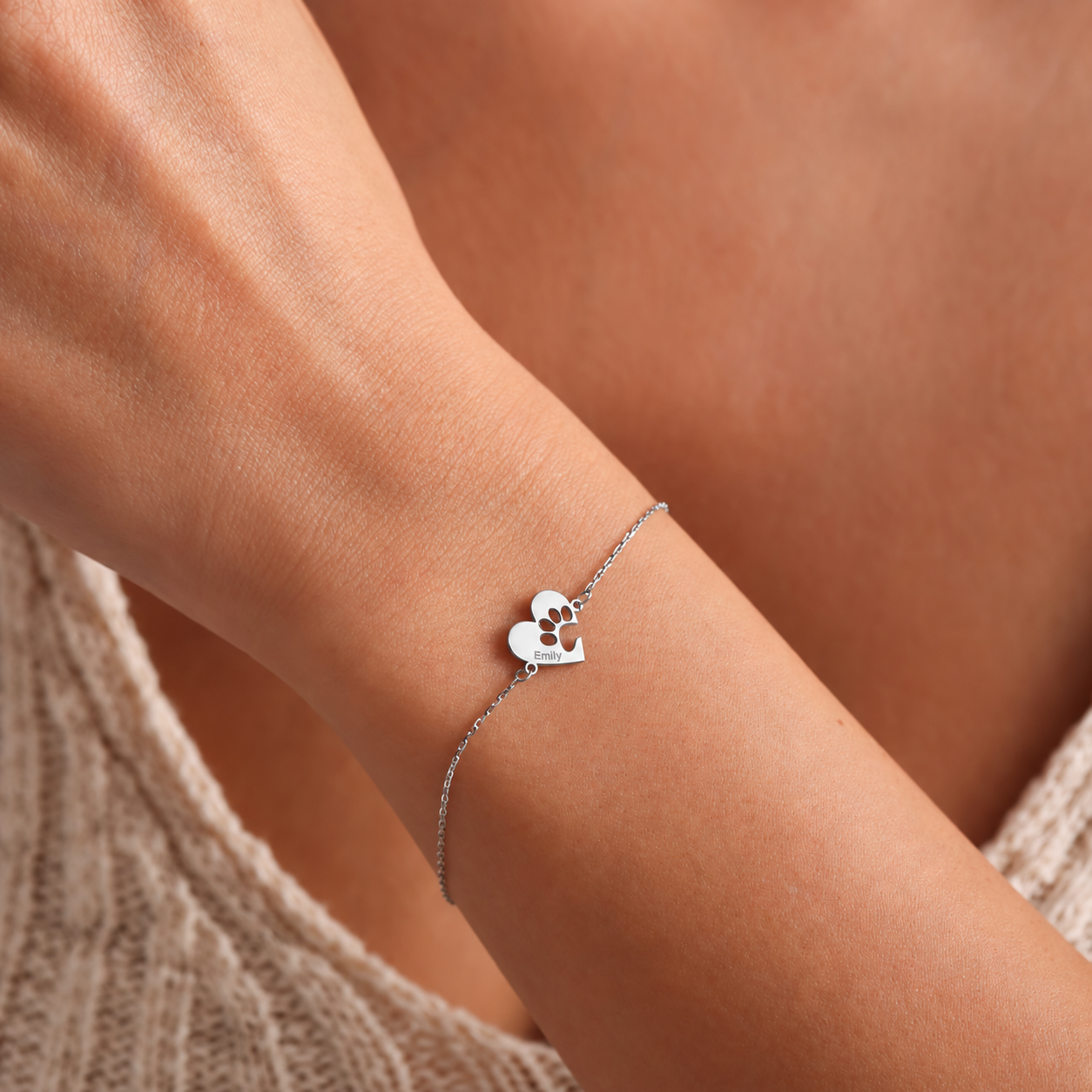 Sterling silver pet paw bracelet with a heart-shaped charm engraved Emily, worn on a wrist