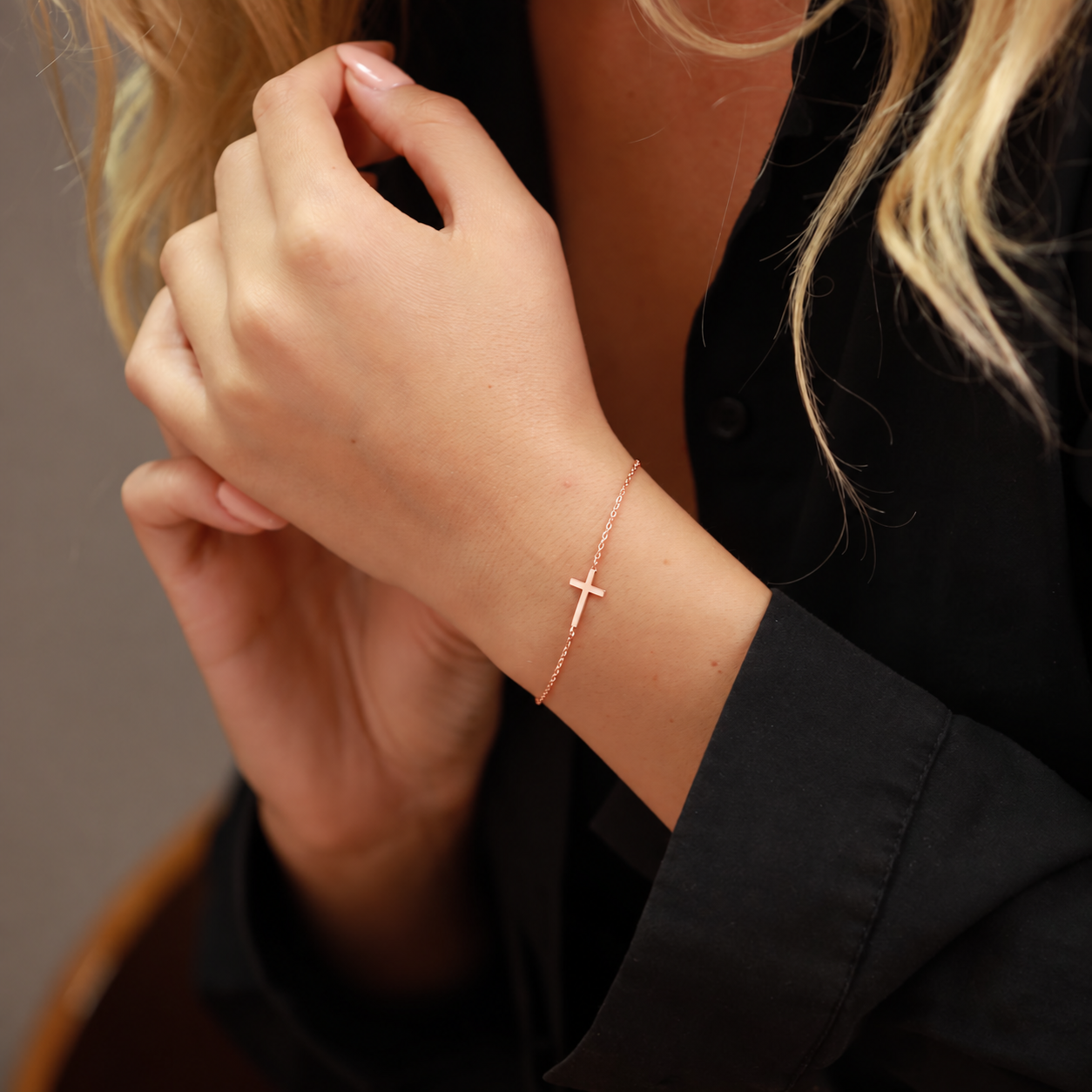 Dainty cross bracelet in 14K rose gold filled, worn on the wrist with a black shirt