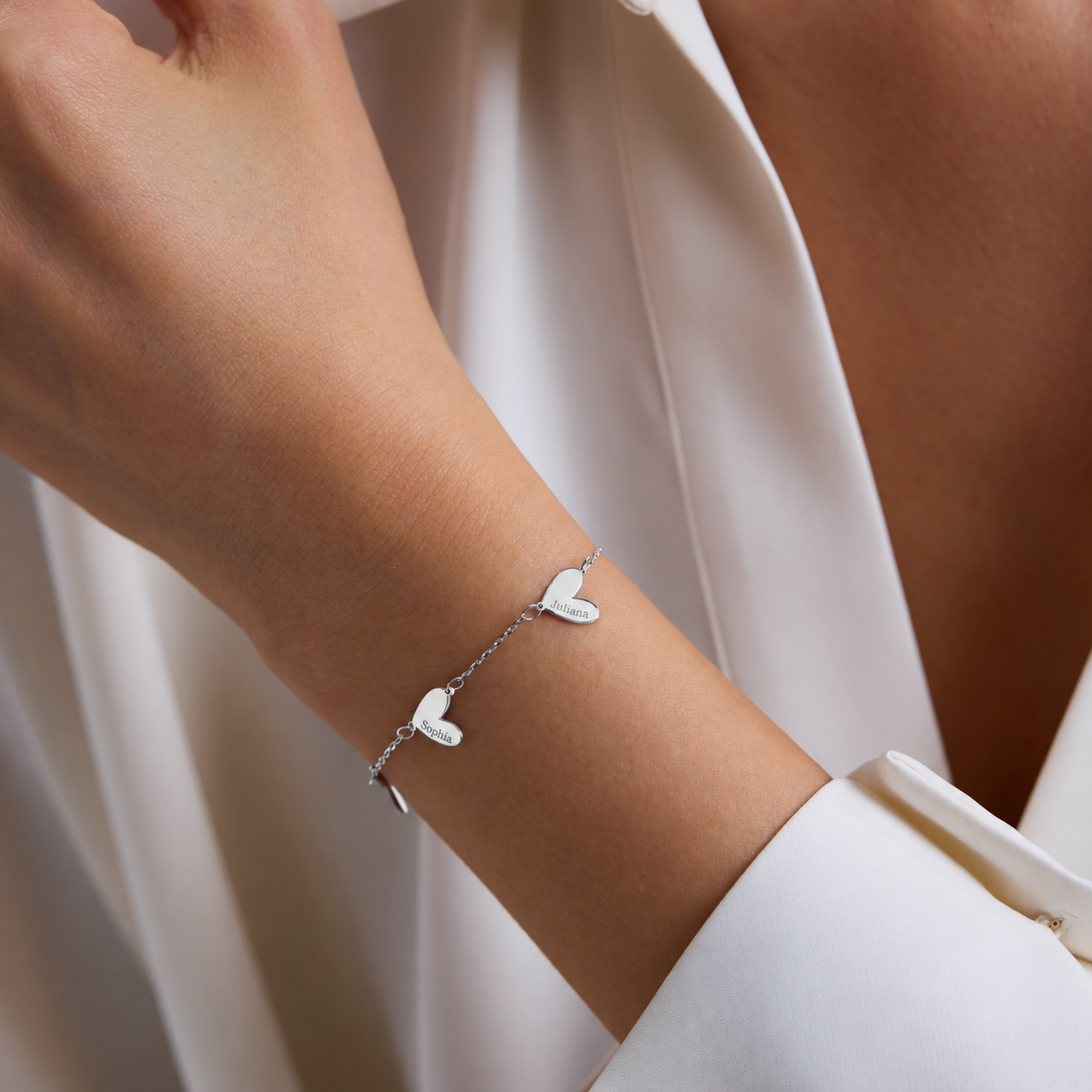 Engraved family heart bracelet in solid white gold, with Juliana and Sophia charms worn with a white shirt