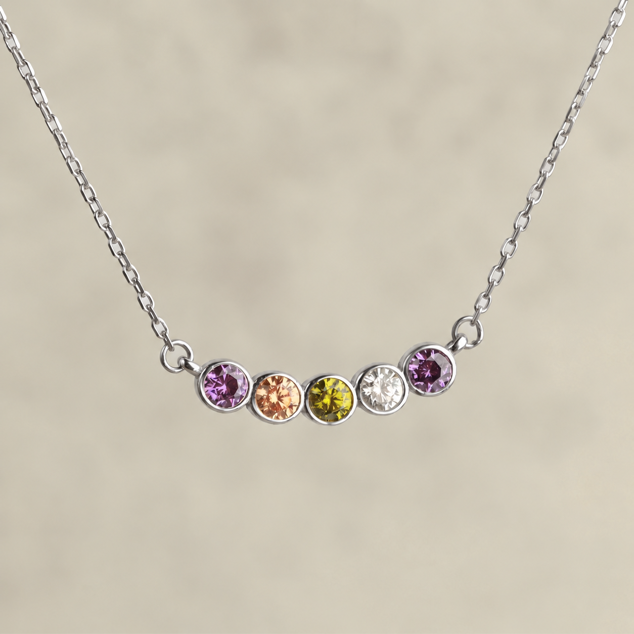 Family birthstone necklace in solid white gold with five colourful gemstones, close-up on a neutral background