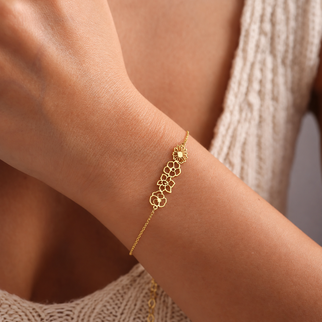 14K solid gold personalized birth flower bracelet with four linked openwork flower charms, worn on a wrist